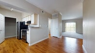 This 1-bedroom, 1-bathroom unit is thoughtfully designed across a single floor, offering a comfortable and functional layout. The open-concept kitchen features stainless steel appliances including a refrigerator and range, light wood cabinetry, granite-style countertops, and a peninsula that connects seamlessly to the living and dining areas. Rich hardwood flooring runs throughout the kitchen and main living spaces, adding warmth and visual continuity.

The living area is generously proportioned, highlighted by elegant crown molding, neutral-toned walls, and a large sliding glass door fitted with vertical blinds that fills the room with natural light and provides access to an outdoor area. A secondary window further enhances the bright, airy ambiance.

The bedroom is a comfortable retreat, complete with plush carpet flooring, a ceiling fan with light fixture, and a window with outdoor views. It is complemented by a spacious walk-in closet outfitted with wire shelving and hanging rods on multiple sides, offering ample storage.

The bathroom features a wide vanity with a granite-style countertop, white cabinetry, and a medicine cabinet mirror. Hardwood flooring in the bathroom transitions to carpet in the hallway, tying the unit together with a cohesive design aesthetic throughout.
