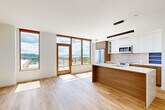 This thoughtfully designed 3-bedroom, 1-bathroom residence at 600 Howard Rd SE in Washington, DC offers a bright, modern living experience across a single floor. Light hardwood flooring flows throughout, complementing the clean white walls and contemporary aesthetic.

The open-concept kitchen, dining, and living area serves as the heart of the home, featuring a striking central island with an undermount sink and white quartz countertops. The kitchen is outfitted with stainless steel appliances, warm wood cabinetry paired with sleek white upper cabinets, and a tiled backsplash. Floor-to-ceiling windows with warm wood frames flood the space with natural light and frame sweeping panoramic views of the Washington, DC skyline and surrounding greenery. A private patio provides direct outdoor access, extending the living space.

Three well-proportioned bedrooms, each with dedicated closets, offer comfort and flexibility, including a spacious primary bedroom with oversized windows capturing elevated outdoor views. The full bathroom features a wood-accented floating vanity, a large backlit mirror, and light tile flooring. A dedicated laundry area and a den add functional versatility. A hallway connects all rooms in a logical, efficient layout, making this a well-appointed residence in Southeast DC.
