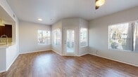 This single-floor residence offers a thoughtfully designed layout with consistent warm-toned hardwood-style flooring running throughout every room, creating a cohesive and inviting atmosphere. The living area is bright and open, featuring multiple windows dressed with white horizontal blinds that allow natural light to filter in, along with a ceiling fan and a private glass-panel exterior door that connects to the outdoors. The angled wall configuration near the entry adds a distinctive architectural touch to the space.

The kitchen is well-equipped with rich dark-wood cabinetry, stainless steel appliances including a range, microwave, and dishwasher, and crisp white quartz-style countertops that extend to a peninsula. A stainless steel sink is positioned beneath a window, enhancing the workspace with natural light.

The bedrooms are generously sized, each fitted with ceiling fans and windows that bring in outdoor views and natural light. The bathroom mirrors the kitchen's design aesthetic with matching dark cabinetry, a white countertop vanity, a tub-shower combination, and hardwood-style flooring. A dedicated laundry room houses a full-size washer and dryer alongside a water heater, adding functional convenience. Overall, the space presents a clean, modern, and practical interior.