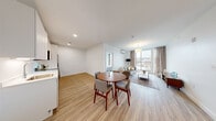 Located at 5 E Pleasant St in Amherst, MA, this thoughtfully designed 2-bedroom, 1-bathroom unit offers a efficient and modern single-floor layout. The open-plan living, dining, and kitchen area forms the heart of the unit, where light wood-tone flooring flows throughout, creating a cohesive and contemporary aesthetic. Large floor-to-ceiling windows in the living room flood the space with natural light while providing outdoor views, and a wall-mounted mini-split system ensures year-round comfort.

The kitchen features flat-front white cabinetry extending to the ceiling, white quartz countertops, and a full suite of stainless steel appliances, including a range, built-in microwave, dishwasher, and refrigerator. The adjacent dining area provides a dedicated space for everyday meals.

Both bedrooms are finished with neutral carpet, crisp white walls, and closets with sliding doors. The shared bathroom includes a tub-shower combination and wood-tone flooring consistent with the rest of the unit. A hallway off the dining area conveniently houses in-unit washer and dryer, adding practical functionality to this well-appointed space.