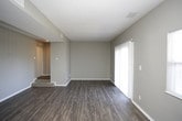 This single-floor residence offers a thoughtfully arranged layout with a variety of finishes throughout. The living area is a generously sized, open space featuring dark hardwood-style flooring and neutral gray walls, with a sliding glass door and an additional window allowing natural light to fill the room and providing views to the outdoors. A subtle step-down transition leads toward the entryway, adding a subtle architectural detail to the space.

The kitchen is well-equipped and features rich dark espresso cabinetry paired with light countertops and a white subway tile backsplash. Black appliances, including a refrigerator, gas range, and dishwasher, complement the cabinetry, while warm-toned hardwood-style flooring ties the space together. A flush-mount ceiling light provides ample overhead illumination.

The bedrooms are carpeted in a neutral tone and each include a sliding-door closet with built-in shelving, offering practical storage. Gray walls and textured ceilings carry throughout these rooms consistently.

The bathroom features dark hardwood-style flooring, a full-sized soaking tub with a white tiled surround, a curved shower rod, and brushed nickel fixtures and grab bar, delivering a clean and functional design.