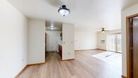 Located at 220 W Valley Rd in Appleton, Wisconsin, this single-floor, 2-bedroom, 1-bathroom residence offers a practical and comfortable layout. Light wood-style flooring flows throughout the main living areas, complemented by clean white walls and warm wood-tone trim and door accents, creating a bright, neutral aesthetic throughout.

The family room is a highlight of the space, featuring a ceiling fan, a wall-mounted AC unit, and a sliding glass patio door that invites natural light and outdoor views. It opens seamlessly into the dining area, which connects directly to the galley-style kitchen. The kitchen is well-appointed with ample warm wood cabinetry on both sides, white appliances including a refrigerator and electric range, a dishwasher, a microwave, and light countertops — offering generous storage and prep space.

A central hallway leads to both bedrooms, each carpeted for comfort and bathed in natural light from well-positioned windows. The primary bedroom includes a walk-in closet with built-in shelving, while the second bedroom features its own closet. Five closets total ensure excellent storage throughout the unit. The full bathroom includes a tub/shower combo and wood-style flooring, finished with a clean, minimal design. Baseboard heating is present throughout the unit.