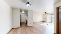 Located at 220 W Valley Rd in Appleton, Wisconsin, this single-floor, 2-bedroom, 1-bathroom residence offers a practical and comfortable layout. Light wood-style flooring flows throughout the main living areas, complemented by clean white walls and warm wood-tone trim and door accents, creating a bright, neutral aesthetic throughout.

The family room is a highlight of the space, featuring a ceiling fan, a wall-mounted AC unit, and a sliding glass patio door that invites natural light and outdoor views. It opens seamlessly into the dining area, which connects directly to the galley-style kitchen. The kitchen is well-appointed with ample warm wood cabinetry on both sides, white appliances including a refrigerator and electric range, a dishwasher, a microwave, and light countertops — offering generous storage and prep space.

A central hallway leads to both bedrooms, each carpeted for comfort and bathed in natural light from well-positioned windows. The primary bedroom includes a walk-in closet with built-in shelving, while the second bedroom features its own closet. Five closets total ensure excellent storage throughout the unit. The full bathroom includes a tub/shower combo and wood-style flooring, finished with a clean, minimal design. Baseboard heating is present throughout the unit.