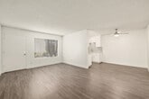 This 1-bedroom, 1-bathroom unit offers a thoughtfully organized single-level layout with a clean, contemporary aesthetic throughout. Consistent wood-look flooring flows through every room, complemented by crisp white walls and textured ceilings that add subtle visual depth.

The living room is the largest open area in the unit, bathed in natural light from a wide window fitted with horizontal blinds. A ceiling fan provides additional airflow, and the generous floor space allows for a variety of furniture arrangements.

The galley-style kitchen is a standout feature, lined on both sides with white shaker cabinetry, light quartz countertops, and a cool-toned subway tile backsplash. Stainless steel appliances — including a refrigerator, gas range, and dishwasher — are neatly integrated, and a skylight overhead floods the space with natural light. A deep undermount sink with a modern faucet completes the functional workspace.

The bedroom is a comfortable and well-proportioned retreat featuring a wide sliding-door closet, a window with blinds, and the same wood-look flooring found throughout the unit.

The bathroom is clean and straightforward, featuring a full tub-shower combination with a white surround and chrome fixtures, a toilet, and a vanity area. The space maintains the same bright, neutral tone as the rest of the unit.