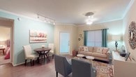 This single-floor residence offers a well-organized layout that balances comfort and functionality throughout its key living spaces. The open living and dining area serves as the heart of the home, featuring crown molding, warm wood-look flooring, and a combination of track and ceiling lighting. Teal curtains frame windows that invite natural light, while a full-glass exterior door connects the space to the outdoors. A cozy dining nook with a round table sits adjacent to the living area, which accommodates a plush sofa, accent chairs, and a patterned area rug.

The kitchen is efficiently designed in a U-shaped configuration, outfitted with white cabinetry, dark countertops, and a full suite of appliances including a range, dishwasher, and microwave. A window above the sink provides natural light and ventilation.

Two bedrooms offer comfortable retreats, each with ceiling fans, carpeted floors, and closet storage. The rooms are softly lit and sized to comfortably accommodate standard bedroom furnishings. Two bathrooms serve the unit, each featuring a tub-shower combination. One bathroom includes a vanity with dark countertops and white cabinetry, while the other offers a more compact, functional layout with wood-look flooring throughout.