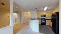 This single-level residence in Marietta, Georgia offers a practical and well-organized layout with clearly defined living, kitchen, and sleeping areas. The kitchen serves as a central feature of the space, equipped with light maple-toned cabinetry, dark countertops, and a full suite of black appliances including a range, over-the-range microwave, and refrigerator. Dark hardwood-style flooring grounds the kitchen area, while a curved peninsula breakfast bar provides a natural transition into the adjoining living area, which is finished with neutral wall-to-wall carpeting.

The living area is open and airy, benefiting from the connected layout that promotes a sense of spaciousness. A ceiling fan adds functional comfort to the space. The bedroom is a well-proportioned, carpeted room with a window that allows natural light to filter in, contributing to a bright and comfortable atmosphere. The bathroom features tile flooring, a vanity with dark countertops and light wood cabinetry, a wall-mounted mirror, and standard fixtures. Throughout the unit, neutral tones in white and beige create a clean, cohesive aesthetic. The 3D floor plan confirms a compact but efficiently arranged floor plan suitable for everyday living.