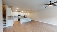 Located at 108 Mechanic St in McDonough, Georgia, this two-story home offers a thoughtfully designed layout across two floors. The main level features a bright, open-concept kitchen and living area bathed in natural light from multiple windows. The kitchen is a standout highlight, showcasing white shaker cabinetry, granite countertops, a subway tile backsplash, stainless steel appliances, and a large center island with pendant lighting — ideal for both cooking and entertaining. The living room is complemented by a ceiling fan and a welcoming front entry door with transom window. Light hardwood-style flooring flows consistently throughout both levels, creating a clean, cohesive aesthetic. The main level also includes an attached garage with concrete flooring and interior access. Upstairs, the upper level houses all three bedrooms, including a generously sized primary bedroom. The upper hallway features recessed lighting and attic access. Each of the three bathrooms includes tub/shower combinations with brushed nickel fixtures and granite-topped vanities. A dedicated laundry room equipped with a full-size Samsung washer and dryer adds everyday convenience. A walk-in closet with rod shelving rounds out the upper level's practical storage offerings.