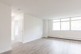 Located at 1 Rosemount Dr in Toronto's Scarborough neighbourhood, this well-appointed 2-bedroom, 1-bathroom unit offers a thoughtfully designed single-floor layout with a clean, modern aesthetic throughout. Light wood laminate flooring runs seamlessly across every room, complemented by crisp white walls and bright white trim that create a fresh, airy atmosphere.

The living room is a standout feature, boasting a large floor-to-ceiling multi-pane window that floods the space with natural light and frames pleasant views of the surrounding greenery. Baseboard heating lines the perimeter, ensuring year-round comfort. The layout connects naturally to the kitchen, which is outfitted with white cabinetry, a subway tile backsplash, stainless steel appliances including a range and over-the-range microwave, and light countertops.

The primary bedroom is generously proportioned and benefits from its own natural light source, while the second bedroom is compact yet functional, featuring built-in sliding closet doors. Both rooms continue the consistent light flooring and neutral palette found throughout the unit. The bathroom is finished with classic white subway tile surrounding a full soaker tub and shower combo, chrome fixtures, and a clean, timeless design. This unit offers a bright, move-in ready living experience in a well-connected Toronto location.