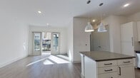 This well-appointed 2-bedroom, 2-bathroom residence offers a thoughtfully designed single-story layout with modern finishes and a bright, open feel. The open-concept living and dining area features light gray wood-style flooring, recessed lighting, and large glass sliding doors that lead to a private outdoor patio, flooding the space with natural light and providing seamless indoor-outdoor access.

The kitchen is a standout feature, showcasing white shaker cabinetry with matte black hardware, dark gray countertops, a herringbone-patterned tile backsplash, a stainless steel farmhouse-style faucet, and a full suite of stainless steel appliances. A central island with pendant lighting adds both prep space and a casual gathering point.

Both bedrooms are carpeted and bright, with the primary bedroom offering generous proportions and a walk-in closet with dual hanging rods and shelving. The primary bathroom is elegantly finished with a dual-sink vanity featuring light gray cabinetry, white countertops, framed mirrors, large-format wood-look tile flooring, a glass-enclosed shower, and a separate soaking tub. A second closet provides additional storage. The exterior features contemporary dark-panel siding and a covered entry walkway.