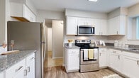 This single-story, two-bedroom, two-bathroom residence in Farmington Hills, Michigan, offers a thoughtfully designed layout with a neutral palette and contemporary finishes throughout. The entryway opens to wood-look flooring that flows into the kitchen and utility areas, creating a cohesive transition between spaces.

The kitchen is a functional highlight, featuring crisp white shaker cabinetry, granite-style countertops, a classic subway tile backsplash, and a full suite of stainless steel appliances including a refrigerator, range, and over-the-range microwave. A window above the sink brings in natural light, enhancing the clean, modern aesthetic.

The open dining area connects seamlessly to the living room, which is anchored by a large sliding glass door offering direct outdoor access and views of lush greenery. Plush carpeting runs through the living, dining, and bedroom areas, contributing to a warm and comfortable atmosphere.

Both bedrooms are generously proportioned with carpet flooring and windows that admit natural light. The two bathrooms include white vanity cabinetry with granite-style counters and glass-enclosed shower stalls. A dedicated in-unit laundry room with full-size washer and dryer adds significant everyday convenience to this well-rounded residence.