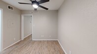 Located on North Lamar Boulevard in Austin's 78751 zip code, this one-bedroom, one-bathroom unit offers a thoughtfully renovated interior designed to maximize its compact footprint. Light wood-style vinyl plank flooring runs consistently throughout the space, creating a cohesive and clean aesthetic.

The galley-style kitchen is efficiently arranged, featuring white shaker cabinetry with matte black hardware, white quartz countertops, a stainless undermount sink with a black faucet, and open shelving for additional storage. Black stainless appliances, including a range and refrigerator, complete the functional kitchen setup.

The main living area benefits from natural light through a window with blinds and is equipped with a ceiling fan, contributing to comfort and airflow. Crown molding details add a subtle architectural touch to this area.

The bedroom is a dedicated, private space with a ceiling fan and clean neutral walls. The bathroom features a full tub-shower combination with white tile surround, matte black fixtures and curtain rod, a toilet, and matching light wood-style flooring, maintaining the unit's consistent design language throughout.
