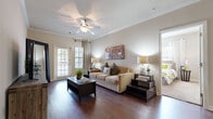 This single-floor residence offers a thoughtfully designed layout that balances comfort and functionality across its living spaces. The living room serves as the heart of the home, featuring rich dark hardwood-style flooring, crown molding, and a ceiling fan overhead. Natural light enters through French doors on one side and a window framed by neutral drape panels on the other, providing dual outdoor access and a bright, open ambiance. A dedicated dining area sits adjacent to the living space, accented by the same hardwood flooring and crown molding detailing.

The galley-style kitchen is efficiently arranged with warm wood cabinetry lining both walls, granite-style countertops, and stainless steel appliances including a range, microwave, and refrigerator, all set above durable wood-look flooring.

The bedrooms offer plush carpeting and ceiling fans, with windows dressed in grommet-panel curtains that filter natural light effectively. Storage is well addressed, with one bedroom featuring a double-door closet and another benefiting from a spacious walk-in closet complete with wire shelving systems.

The bathroom includes tile flooring, wood cabinetry with dark countertops, and a full tub-shower combination, rounding out this cohesive and practical residence.
