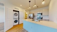 This thoughtfully designed one-bedroom, one-bathroom unit in Fort Collins, Colorado offers a clean, modern aesthetic throughout. The open-concept kitchen serves as the heart of the home, featuring a large peninsula with a sleek white countertop, an undermount sink, and stylish pendant lighting overhead. Stainless steel appliances — including a refrigerator, gas range, and over-the-range microwave — are complemented by crisp white cabinetry and a classic subway tile backsplash. Light hardwood-style flooring flows through the main living areas, adding warmth to the bright, neutral palette. A standout feature is the in-unit stacked washer and dryer, conveniently tucked just off the kitchen. The living area is bright and open, with natural light filtering through window blinds. The bedroom is carpeted for comfort, with a large window offering outdoor views and connecting doors to both a dedicated closet and the bathroom. The full bathroom is clean and well-appointed, featuring a shower-tub combo, white cabinetry with modern hardware, and matching light hardwood-style flooring. Throughout the unit, recessed lighting and simple, contemporary design choices create a cohesive and functional living environment ideal for those seeking a move-in-ready space.