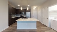 This single-floor residence on Coburg Road in Charleston, South Carolina, showcases a contemporary design with a thoughtful, open layout. The heart of the home is a well-appointed kitchen featuring dark espresso cabinetry, stainless steel appliances, a subway tile backsplash, and a generously sized island with granite countertops and pendant lighting overhead. Wood-look plank flooring flows throughout the main living areas, complementing the kitchen's modern aesthetic.

The bedrooms are finished with plush carpeting and feature large windows fitted with blinds, allowing for ample natural light and views of the surrounding neighborhood. Ceiling fans add functional comfort to these restful spaces.

The bathrooms are elegantly designed with light tile flooring, granite vanity countertops, and dark cabinetry. Each bathroom provides access to a walk-in closet outfitted with built-in shelving and hanging rods, offering substantial storage. One bathroom includes a soaking tub with a tiled surround and grab bar, while another features a separate tiled shower.

Throughout the residence, neutral tones and clean architectural lines create a cohesive, modern ambiance. The open-concept design promotes a seamless connection between the kitchen and living areas, making the space feel inviting and well-organized.