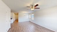 Located at 111 NW 63rd Ave in Highfill, Arkansas, this single-story, 3-bedroom, 2-bathroom home offers a thoughtfully designed layout that maximizes functionality and comfort. Consistent hardwood-style flooring flows throughout the entire home, creating a cohesive and clean aesthetic from room to room.

The open-concept living area is bright and welcoming, featuring a ceiling fan with a light fixture and a stylish chandelier that adds a touch of elegance. Natural light filters in through windows fitted with blinds, enhancing the airy feel of the space. The living area connects seamlessly to the kitchen and dining zone, making it ideal for everyday living and entertaining.

The kitchen is well-equipped with crisp white cabinetry, dark countertops, a double-basin sink, and black appliances including a range, microwave, and dishwasher. Recessed lighting illuminates the space efficiently, and ample cabinet storage lines both sides of the galley-style layout.

Each of the three bedrooms is outfitted with a ceiling fan, neutral wall tones, and hardwood-style flooring. The primary bedroom offers a generous footprint with good natural light. Both bathrooms feature clean, white tub-shower combinations with brushed nickel fixtures, offering a fresh and functional design. A dedicated closet provides additional storage, completing this practical and move-in-ready home.