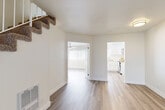Located at 6401 Warner Ave in Huntington Beach, California, this two-story home offers three bedrooms and five bathrooms across two thoughtfully laid-out floors. The main level opens into a bright, airy living room featuring light wood-look flooring, clean white walls, and vertical blinds that filter natural light. A staircase with metal railings connects both floors, adding a clean, modern architectural detail. The kitchen is a standout feature, showcasing crisp white shaker cabinets, white countertops, stainless steel appliances including a range and over-the-range microwave, and a peninsula that doubles as a casual dining area. Light wood flooring carries through the kitchen, maintaining a cohesive look throughout the main living areas. The upper floor hosts the bedrooms, which feature plush carpeting and windows with vertical blinds that allow natural light while providing privacy. The spacious primary bedroom offers a comfortable and restful retreat. The five bathrooms are finished with white vanities, clean countertops, and mirrors, reflecting a consistent, neutral aesthetic throughout the home. A carpeted staircase connects the floors, and a hallway ties the upper-level rooms together efficiently. The overall ambiance is clean, bright, and move-in ready, ideal for comfortable living in a prime Southern California location.