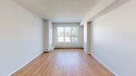 Located at 466–470 Macewan Rd SW in Edmonton, Alberta, this well-appointed 2-bedroom, 2-bathroom unit offers a practical and comfortable single-floor layout. The open-concept kitchen and living area serves as the heart of the home, featuring warm hardwood flooring, a textured ceiling, and generous natural light. The kitchen is equipped with stainless steel appliances — including a refrigerator, electric range, and built-in microwave — complemented by light-toned cabinetry, a stone-look countertop, and a peninsula with a double undermount sink. Pendant lighting and track lighting add both style and functionality to the space. The living area benefits from a large window framing views of mature trees, creating a bright and inviting atmosphere. Both bedrooms offer hardwood flooring, neutral walls, and natural light, with the primary bedroom featuring dual windows overlooking the wooded surroundings. The two bathrooms include a vanity with a stone countertop and a full tub-shower combination. Four closets and a dedicated laundry area provide ample storage throughout. A built-in shelving unit near the entryway adds practical organization. Baseboard heating is present throughout the unit, ensuring year-round comfort.