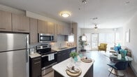 This single-story residence in Conroe, Texas offers a thoughtfully designed open-concept layout that maximizes functionality and flow. The kitchen serves as a central highlight, featuring stainless steel appliances including a refrigerator, electric range, microwave, and dishwasher. Two-toned cabinetry pairs light upper cabinets with dark lower cabinets, complemented by light quartz countertops. A kitchen island with pendant lighting above provides additional prep and dining space, while wood-look flooring extends throughout the main living areas.

The living room benefits from large floor-to-ceiling windows and a sliding glass door that opens to a private balcony, flooding the space with natural light and offering views of the surrounding community. A ceiling fan adds to the comfort of the room.

Both bedrooms feature plush carpeting, ceiling fans, and windows fitted with blinds. The two bathrooms are finished with tile flooring, one offering a shower/tub combination with subway tile surround, and the other featuring a walk-in shower. Each bathroom includes dark wood cabinetry and a vanity mirror. The overall aesthetic is contemporary and cohesive throughout.