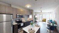 This single-story residence in Conroe, Texas offers a thoughtfully designed open-concept layout that maximizes functionality and flow. The kitchen serves as a central highlight, featuring stainless steel appliances including a refrigerator, electric range, microwave, and dishwasher. Two-toned cabinetry pairs light upper cabinets with dark lower cabinets, complemented by light quartz countertops. A kitchen island with pendant lighting above provides additional prep and dining space, while wood-look flooring extends throughout the main living areas.

The living room benefits from large floor-to-ceiling windows and a sliding glass door that opens to a private balcony, flooding the space with natural light and offering views of the surrounding community. A ceiling fan adds to the comfort of the room.

Both bedrooms feature plush carpeting, ceiling fans, and windows fitted with blinds. The two bathrooms are finished with tile flooring, one offering a shower/tub combination with subway tile surround, and the other featuring a walk-in shower. Each bathroom includes dark wood cabinetry and a vanity mirror. The overall aesthetic is contemporary and cohesive throughout.
