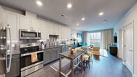 This 1-bedroom, 1-bathroom residence is designed with a modern aesthetic and an efficient open-concept floor plan that maximizes every square foot. The kitchen serves as a central focal point, featuring two-tone cabinetry in white and grey, granite countertops, a decorative tile backsplash, and a full suite of stainless steel appliances including a refrigerator, range, microwave, and dishwasher. A freestanding kitchen island with bar seating provides additional prep space and casual dining options. Wide-plank hardwood flooring flows seamlessly from the kitchen into the living area, which is bright and inviting thanks to large sliding glass doors that open onto a private balcony overlooking lush tree canopy views. Recessed lighting throughout ensures consistent, well-distributed illumination. The bedroom is a comfortable retreat featuring a warm accent wall, a large window with balcony access, and soft carpeting underfoot. It connects directly to a dedicated walk-in closet with multi-tiered wire shelving for organized storage. The bathroom is finished with patterned tile flooring, a granite-topped vanity, and a glass-enclosed walk-in shower with elegant black frame detailing and subway tile surround.