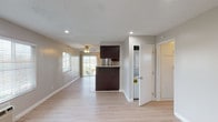 This single-floor unit offers a clean, functional layout with a cohesive design carried throughout. Light wood-tone flooring runs continuously across the living areas, bedrooms, and common spaces, contributing to a bright, open feel. The main living area is generously proportioned, featuring recessed lighting, a wall-mounted HVAC unit, and multiple windows fitted with horizontal blinds that allow ample natural light to fill the space.

The kitchen is well-appointed with rich dark wood cabinetry, granite-style countertops, a stainless steel gas range with overhead exhaust hood, and a double-basin sink. A peninsula-style counter separates the kitchen from the adjoining living space, enhancing flow and functionality. In-unit stacked laundry is conveniently located just off the kitchen area.

The bedrooms are comfortably sized, each equipped with ceiling fans with light fixtures and windows offering outdoor views. One bedroom features a closet with built-in shelving. The bathroom includes a full tub-shower combination with white subway tile surround, chrome fixtures, and a small window providing natural ventilation. Textured ceilings and neutral gray walls complete the interior throughout.