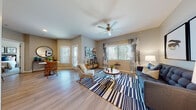 This single-floor residence offers a thoughtfully designed layout with a seamless flow between living spaces. The open-concept living and dining area is anchored by light wood-look flooring, a ceiling fan, and multiple windows dressed with vertical blinds and sheer curtains, allowing generous natural light while maintaining privacy. A glass panel door leads to an outdoor area, further enhancing the bright, airy atmosphere.

The kitchen is well-equipped with walnut-toned cabinetry, granite countertops, white appliances, and a peninsula with bar seating. An in-unit washer and dryer are conveniently accessible from the kitchen corridor. The dining area accommodates a bistro-style table and benefits from its own exterior door, providing easy outdoor access.

Both bedrooms feature plush carpeting and multiple windows. The primary bedroom includes a walk-in closet and ample space for a king-sized bed. The bathroom showcases wood-grain cabinetry, granite countertops, a large mirror with vanity lighting, and wood-look flooring throughout. Neutral warm-beige walls unify the space, creating a cohesive and inviting atmosphere suited for comfortable everyday living.