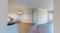 This single-floor, 2-bedroom, 2-bathroom home offers a functional and thoughtfully designed layout across a comfortable footprint. The open-concept living and dining area features wood-look laminate flooring, crown molding, and a classic white-mantled fireplace with an arched niche above it, serving as the room's focal point. The dining area is defined by a chandelier overhead and a chair rail that runs along the walls, adding a refined architectural detail. Adjacent to the living space, the kitchen features white cabinetry, subway tile backsplash, track lighting, and a peninsula with a dark countertop that provides additional prep space and opens toward the main living area. Both bedrooms are carpeted and include ceiling fans, arched transom windows that invite natural light, and generous closet space with built-in wire shelving systems. The primary bedroom is a comfortable size, offering ample room for furnishings. The two bathrooms are finished with wood-look flooring, white vanity cabinetry, dark countertops, large mirrors, and a shower-tub combination. Two hallways connect the home's spaces efficiently, and two closets provide practical storage throughout.