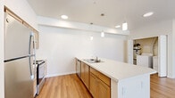 Located in Spokane, WA, this well-designed one-bedroom, one-bathroom unit offers a comfortable and functional single-floor layout. The open-concept kitchen and living area serves as the heart of the home, featuring warm-toned wood cabinetry, stainless steel appliances, a double-basin sink, and a generous peninsula with a white countertop that provides both additional prep space and casual seating. Pendant lighting and recessed ceiling lights brighten the kitchen, which flows seamlessly into the living area. The living room is finished with hardwood-style flooring and benefits from abundant natural light streaming through large windows and a private exterior door that opens to an outdoor view of green surroundings. The spacious bedroom is carpeted for comfort, offering a tranquil retreat with a window overlooking the outdoors, a baseboard heating unit, and a large sliding double-door closet for ample storage. The bathroom includes a full tub and shower combination with clean white surrounds and hardwood-style flooring. Additional highlights include in-unit laundry access, hallway connectivity between rooms, and a neutral, light-filled palette throughout that creates a clean and inviting ambiance.