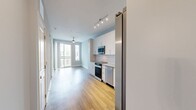 Located at 940 E Adams St in Jacksonville, FL, this well-appointed one-bedroom, one-bathroom unit offers a thoughtfully designed single-floor layout with a clean, modern aesthetic. The open-plan kitchen and living area serves as the heart of the home, showcasing warm hardwood-style flooring, soft gray walls, and track lighting overhead. The kitchen is outfitted with sleek white cabinetry, granite countertops, a classic white subway tile backsplash, and a full suite of stainless steel appliances including a range, microwave, dishwasher, and French door refrigerator. The living area extends to a private balcony through sliding glass doors, inviting natural light and outdoor views into the space. The bedroom is carpeted for comfort, features a ceiling fan, and is brightened by multiple windows with blinds. The bathroom is spacious and well-appointed, featuring dual undermount sinks set into granite countertops, white cabinetry, large mirrors, wood-look flooring, and a glass-enclosed shower. A dedicated closet provides practical storage. The unit combines modern finishes with functional design, creating a comfortable and stylish living environment in the heart of Jacksonville.