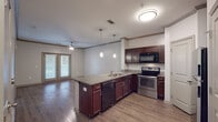 This single-floor residence offers a thoughtfully designed open-concept layout that seamlessly connects the kitchen, dining, and living areas. The kitchen serves as the centerpiece of the home, showcasing rich dark wood cabinetry, granite countertops, and a peninsula island with pendant lighting overhead. Stainless steel appliances — including a refrigerator, electric range, and built-in microwave — complement the sleek finishes, while a built-in dishwasher adds everyday convenience. Hardwood-style flooring runs throughout the main living areas, enhancing the warm, cohesive aesthetic.

The spacious living area is bathed in natural light through large French doors that open to the outside, and is accented by crown molding and a ceiling fan. The bedrooms are carpeted for comfort and each features a ceiling fan and ample natural light from large windows. The primary bedroom connects to a private en-suite bathroom, which mirrors the kitchen's design language with matching dark cabinetry, granite countertops, a large vanity mirror, a soaking tub, and additional wall-mounted storage. The consistent use of quality finishes and cohesive design elements throughout creates a polished, comfortable living environment.