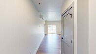This efficiently designed single-floor unit offers a clean, modern aesthetic throughout its well-organized layout. Warm hardwood-style flooring flows seamlessly across the entire space, complementing the crisp white walls and contemporary finishes.

The kitchen is a functional standout, featuring gray shaker-style cabinetry, granite countertops, a classic white subway tile backsplash, and a full suite of stainless steel appliances including a side-by-side refrigerator with ice and water dispenser, electric range with microwave, and dishwasher. The open sightlines between the kitchen and living area create a spacious feel despite the compact footprint.

The living area benefits from a wall-mounted mini-split HVAC system for year-round climate control, and a sliding glass door floods the space with natural light while offering direct access to an outdoor area. An additional window provides pleasant views of surrounding greenery and neighboring architecture.

The bedroom is a comfortable retreat, appointed with a ceiling fan and multiple windows that allow ample natural light to filter in. The bathroom features a full-size tub and shower combination with clean white surround and polished chrome fixtures.

Throughout the unit, modern two-panel interior doors with matte black hardware add a refined design touch, tying the contemporary aesthetic together cohesively.