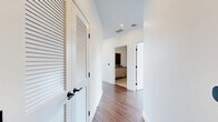 Located in the heart of San Diego at 675 Ninth Avenue, this contemporary two-bedroom, two-bathroom residence offers a striking urban living experience defined by clean lines and an abundance of natural light. The open-concept kitchen and living area serves as the centerpiece of the home, boasting soaring ceilings, rich hardwood-style flooring, and dramatic floor-to-ceiling windows framed in sleek black steel that reveal panoramic downtown skyline views. The gourmet kitchen features a substantial waterfall-edge stone island, light wood cabinetry, a tiled backsplash, pendant lighting, and a full suite of stainless steel appliances. Exposed concrete columns add an industrial architectural accent that complements the modern aesthetic. The living room extends toward a private balcony, further maximizing the expansive city vistas. The primary bedroom is a well-proportioned retreat with its own walk-in closet equipped with built-in shelving and hanging rods. The en-suite primary bathroom showcases large-format stone tile, a glass-enclosed shower, and a wood-toned vanity. The second bedroom also offers a closet with built-in organization. A clean, light-filled hallway with louvered closet doors connects the spaces seamlessly, completing this polished and thoughtfully designed urban residence.