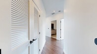 Located in the heart of San Diego at 675 Ninth Avenue, this contemporary two-bedroom, two-bathroom residence offers a striking urban living experience defined by clean lines and an abundance of natural light. The open-concept kitchen and living area serves as the centerpiece of the home, boasting soaring ceilings, rich hardwood-style flooring, and dramatic floor-to-ceiling windows framed in sleek black steel that reveal panoramic downtown skyline views. The gourmet kitchen features a substantial waterfall-edge stone island, light wood cabinetry, a tiled backsplash, pendant lighting, and a full suite of stainless steel appliances. Exposed concrete columns add an industrial architectural accent that complements the modern aesthetic. The living room extends toward a private balcony, further maximizing the expansive city vistas. The primary bedroom is a well-proportioned retreat with its own walk-in closet equipped with built-in shelving and hanging rods. The en-suite primary bathroom showcases large-format stone tile, a glass-enclosed shower, and a wood-toned vanity. The second bedroom also offers a closet with built-in organization. A clean, light-filled hallway with louvered closet doors connects the spaces seamlessly, completing this polished and thoughtfully designed urban residence.