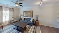 This single-floor residence offers a cohesive blend of modern functionality and warm, inviting design. The open kitchen is a standout feature, outfitted with rich dark cabinetry, granite countertops, stainless steel appliances including a range and refrigerator, a undermount sink, and pendant lighting that adds a polished finishing touch. Wood-look flooring runs throughout the kitchen and living areas, adding warmth and continuity.

The living room exudes a relaxed yet refined ambiance, highlighted by crown molding, hardwood-style floors, a ceiling fan with track lighting, and neutral walls that create an ideal backdrop for comfortable living. A large framed vintage-style map serves as a focal point above the tufted sofa, complemented by rustic wood accent pieces.

The bedroom is carpeted and tranquil, featuring a ceiling fan, large windows dressed with linen drape panels and plantation shutters that allow natural light to filter in softly. The room offers a calm, neutral palette conducive to rest and relaxation.

The bathroom is designed with accessibility in mind, equipped with sturdy grab bars positioned near the toilet and a louvered closet door nearby, all set on durable wood-look flooring. The space is clean, practical, and thoughtfully arranged to accommodate a wide range of needs.