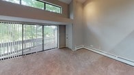 Located at 2542 Woodlake Rd SW in Wyoming, Michigan, this two-story residence offers a well-organized layout across both levels. The main living area is generously proportioned, featuring plush carpeting, baseboard heating, and track lighting overhead. A striking architectural detail is the double-height wall of windows in one section of the living space, allowing abundant natural light to filter in while a ceiling fan promotes air circulation. A warm wood accent beam adds visual interest at the transition between floors, visible from the open lower level.

The galley-style kitchen is equipped with rich medium-toned wood cabinetry, light countertops, wood-look flooring, and stainless appliances including a refrigerator and dishwasher, alongside a gas range. The kitchen opens conveniently toward the main living area.

Bedrooms are carpeted and illuminated by track lighting, each offering a comfortable, neutral palette with baseboard heating. The bathrooms feature wood-look flooring, a tub-shower combination with white tile surround, a vanity with light countertop, and a large mirror.

A dedicated laundry area with a full-size washer and dryer, wood-look flooring, and overhead shelving adds everyday practicality to this well-appointed home.