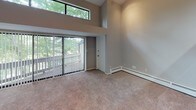 Located at 2542 Woodlake Rd SW in Wyoming, Michigan, this two-story residence offers a well-organized layout across both levels. The main living area is generously proportioned, featuring plush carpeting, baseboard heating, and track lighting overhead. A striking architectural detail is the double-height wall of windows in one section of the living space, allowing abundant natural light to filter in while a ceiling fan promotes air circulation. A warm wood accent beam adds visual interest at the transition between floors, visible from the open lower level.

The galley-style kitchen is equipped with rich medium-toned wood cabinetry, light countertops, wood-look flooring, and stainless appliances including a refrigerator and dishwasher, alongside a gas range. The kitchen opens conveniently toward the main living area.

Bedrooms are carpeted and illuminated by track lighting, each offering a comfortable, neutral palette with baseboard heating. The bathrooms feature wood-look flooring, a tub-shower combination with white tile surround, a vanity with light countertop, and a large mirror.

A dedicated laundry area with a full-size washer and dryer, wood-look flooring, and overhead shelving adds everyday practicality to this well-appointed home.