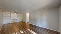 Located at 460 E Dayton Yellow Springs Rd in Fairborn, Ohio, this one-bedroom, one-bathroom unit offers a practical and well-organized single-floor layout. The living room is a standout space, featuring warm hardwood-style flooring, a textured ceiling, a ceiling fan with light fixture, and a distinctive built-in shelving unit with arched accents and lower cabinet storage — ideal for display or media use. Natural light filters through the windows, brightening the neutral gray walls throughout. The entry area includes hardwood-style flooring and a wall-mounted HVAC unit, with an exterior-facing window that brings in additional daylight. The kitchen is efficiently arranged with dark wood cabinetry, granite-style laminate countertops, a stainless steel sink, an electric range, and an overhead ventilation hood. The bedroom features plush carpeting, a ceiling fan, a window with outdoor views, a baseboard heater, and access to a closet. The unit includes a total of three closets, offering generous storage. The bathroom is equipped with a full tub-shower combination. A connecting hallway ties the rooms together, completing this compact yet functional floor plan.