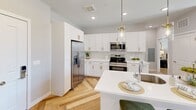 This thoughtfully designed 2-bedroom, 1-bathroom residence at 950 Trout Brook Drive in West Hartford, CT offers a cohesive blend of modern aesthetics and functional living. The open-concept kitchen and living area serves as the heart of the home, featuring white shaker cabinetry with gold hardware, stainless steel appliances, a herringbone-patterned light wood floor, and a central island with a white quartz countertop topped by elegant pendant lighting. The living room is bathed in natural light through large windows and a glass door opening to a private balcony with views of the outdoor amenity area. A textured accent wall adds warmth and depth to the space, complemented by recessed lighting throughout. The primary bedroom is a serene retreat highlighted by an artistic mural-style accent wall, a walk-in closet, and a bright window overlooking the outdoor pool area. The second bedroom is equally well-appointed. The bathroom features a dark vanity with gold hardware, clean white countertops, and wood-look flooring that ties seamlessly into the rest of the residence. Every detail reflects a refined, contemporary design sensibility throughout.