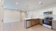 Located at 1154 N Old Castle Rd in Nixa, MO, this single-story home offers a thoughtfully designed layout across three bedrooms and two bathrooms. The open-concept kitchen and living area serves as the heart of the home, showcasing light wood-look flooring, recessed lighting, and pendant lights above a spacious peninsula with a built-in sink. The kitchen features stainless steel appliances, a classic subway tile backsplash, white upper cabinetry, and warm-toned lower cabinets, creating a stylish two-tone aesthetic. The living room is bright and welcoming, with French doors that invite natural light and provide outdoor views, complemented by a ceiling fan and recessed lighting. Each bedroom is finished with plush carpet, neutral-toned walls, and windows that bring in ample daylight. The primary bedroom includes a ceiling fan for added comfort. Both bathrooms are finished consistently with light wood-look tile flooring, white shaker-style vanities with quartz countertops, backlit mirrors, and brushed gold hardware accents, lending a clean and modern feel. A dedicated laundry room adds everyday convenience. The overall ambiance is modern, clean, and move-in ready, with cohesive finishes carried throughout the entire home.