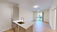 Located at 13901 SW 122nd Ave in Miami, FL, this well-appointed 1-bedroom, 1-bathroom residence offers a clean, modern aesthetic with thoughtful design throughout. The entry hallway, illuminated by track lighting, leads directly into the heart of the home and showcases light wood-tone flooring that flows seamlessly through every room.

The open-concept kitchen and living area serves as the centerpiece of the unit. The kitchen features a peninsula island with a crisp white quartz countertop and an undermount sink, complemented by light wood cabinetry and a full suite of stainless steel appliances, including a refrigerator with ice maker, range, and microwave. Track lighting overhead highlights the contemporary finishes. The adjacent living area is bright and airy, equipped with a ceiling fan and sliding glass doors that open to a private balcony with outdoor views.

The bedroom is a comfortable and well-lit retreat, featuring a large window that invites natural light and a walk-in closet with built-in shelving. The room's neutral tones and hardwood-style flooring create a calm, functional space.

The bathroom is finished in clean white tones, offering a full tub-shower combination with a curved curtain rod, chrome fixtures, tile flooring, and accessibility grab bars for added convenience.