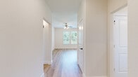 Located at 605 Hunt Rd in Baytown, TX, this single-story, 3-bedroom, 2-bathroom home offers a clean, modern aesthetic with thoughtful finishes throughout. Light wood-look flooring runs continuously across all rooms, creating a cohesive and bright interior. The open kitchen is a standout feature, boasting white shaker cabinetry with matte black hardware, striking marble-veined quartz countertops, a central island, subway tile backsplash, and a full suite of stainless steel appliances including a range, over-the-range microwave, dishwasher, and French door refrigerator. The combined kitchen and living area provides an efficient, open-concept layout. The bedrooms are well-lit, with multiple windows offering views of the surrounding greenery and ceiling fans for added comfort. The primary bedroom includes direct access to a dedicated closet and an en-suite bathroom featuring a glass-enclosed walk-in shower. The second bathroom includes a tub-shower combination and a window for natural light. Both bathrooms are finished with white cabinetry and matte black fixtures. A hallway connects the bedrooms efficiently. The exterior dollhouse view reveals a generous yard, adding valuable outdoor space to this well-appointed home.