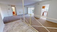 This single-floor residence is organized around a practical split-level layout, where a tiled entryway with a white metal railing transitions up a few steps into the main carpeted living area. The living room is generously sized, featuring neutral-toned carpet, a structural beam accent, and a large sliding glass door fitted with vertical blinds that allows natural light to filter in and provides access to an outdoor balcony with views of surrounding greenery.

Adjacent to the living area, the kitchen is outfitted with warm honey-toned wood cabinetry, dark laminate countertops, tile flooring, and white appliances including a refrigerator, dishwasher, and range. A window above the sink brings in additional natural light.

The bedrooms are carpeted and finished in neutral tones, each offering a calm, understated atmosphere. One bedroom features a walk-in closet with built-in shelving and hanging rods, providing ample storage. A dedicated laundry area with tile flooring and utility hookups adds everyday convenience. The bathroom includes tile flooring and warm wood vanity cabinetry, completing a cohesive, functional interior.