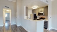 Located at 7240 Corbin Ave in Reseda, California, this single-story residence offers a thoughtfully updated interior with a cohesive, modern aesthetic. The open-concept living area is anchored by rich hardwood-style flooring that reflects natural light streaming in through plantation-shuttered windows. Crown molding and a textured ceiling add architectural character, while a ceiling fan enhances comfort. The living space flows seamlessly into a peninsula-style kitchen, which features gray shaker cabinetry, light quartz countertops, a classic subway tile backsplash, and stainless steel appliances including a refrigerator, gas range, and over-the-range microwave. The bedrooms are finished with plush carpeting, crown molding, and ample closet storage via sliding-door closets. Natural light filters into the bedrooms through shuttered windows offering outdoor views. The unit includes two bathrooms: one featuring a combined shower and tub with glass sliding doors and a granite-topped vanity, and another with a standalone glass-enclosed shower and matching dark granite countertop. Light wood-style flooring in both bathrooms completes the clean, updated look throughout this well-maintained single-floor home.