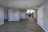 This thoughtfully updated single-floor residence in San Bernardino, California, offers a clean, modern aesthetic throughout. Light-toned luxury vinyl plank flooring runs continuously across the living, dining, and bedroom areas, creating a cohesive and easy-to-maintain foundation. The open-concept living and dining area is bright and welcoming, featuring recessed lighting, a ceiling fan, textured ceilings, and a sliding door that invites natural light from outside. The kitchen is a standout feature, outfitted with crisp white shaker cabinetry, dark countertops, stainless steel appliances including a range and refrigerator, recessed lighting, and ample storage. A peninsula counter connects the kitchen to the main living space, supporting an efficient layout. The bedrooms are generously proportioned with vaulted ceilings that enhance the sense of openness, windows with vertical blinds for light control, and ceiling fans for comfort. The bathrooms are finished in a neutral palette, with white cabinetry, dark countertops, and a combination tub and shower. A second, more compact bathroom provides additional convenience. The overall color scheme of warm greiges, crisp white trim, and brushed nickel hardware lends the space a clean, contemporary character throughout.