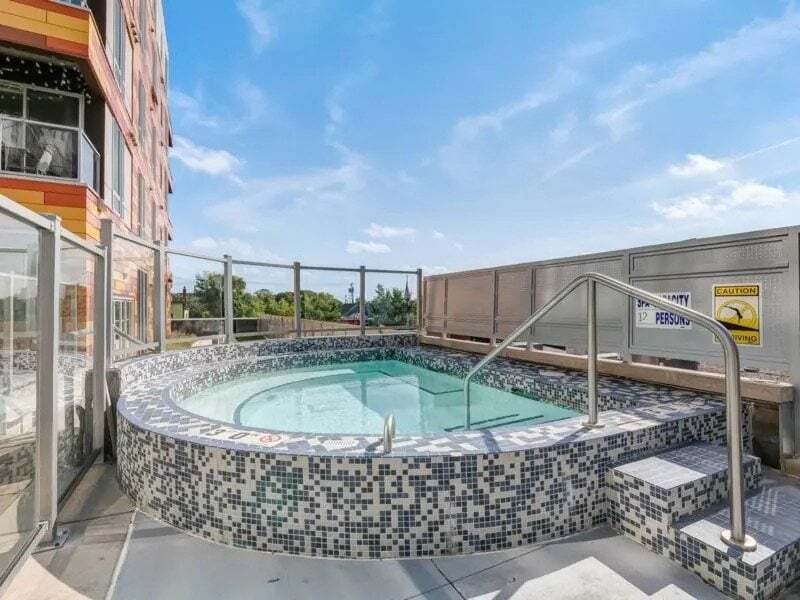 Outdoor jacuzzi on a rooftop deck with a modern building in the background.