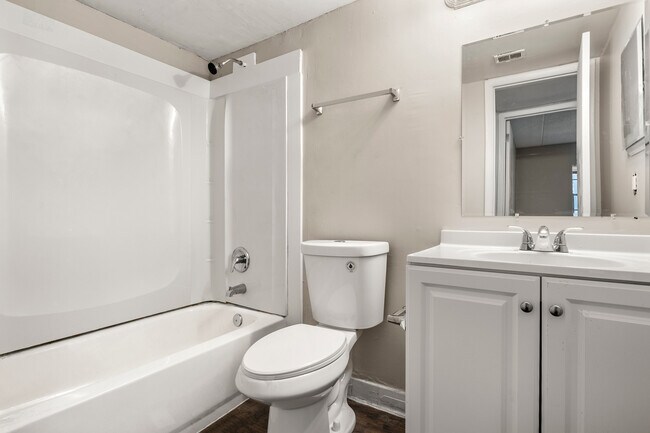 Baño luminoso y acogedor con bañera moderna, tocador elegante y grifería de diseño. - Alderman Park Apartments