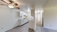Located at 2487 Chestnut Hills Dr in Kalamazoo, Michigan, this 2-bedroom, 1-bathroom residence offers a practical and well-organized single-floor layout with clean, neutral finishes throughout. The galley-style kitchen is a standout feature, equipped with white shaker cabinetry, light stone-look countertops, a stainless steel sink, and white appliances including a range, microwave, and refrigerator. Wood-look vinyl flooring runs through the kitchen and connects to an adjacent dining or living area, which features a ceiling fan and open sightlines to the kitchen. Both bedrooms are carpeted and filled with natural light from windows overlooking lush greenery outside. The primary bedroom is a comfortable size, offering two windows, baseboard heating, and direct access to a dedicated walk-in closet outfitted with dual hanging rods and shelving. The second bedroom also features carpeting, a window, and its own closet access. The full bathroom includes a tub-shower combination, vanity with storage, a toilet, and wood-look vinyl flooring with baseboard heating. Clean white walls and consistent finishes throughout give the space a bright, move-in ready feel.