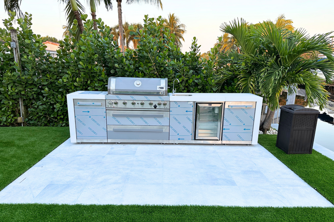 The new outdoor kitchen includes a sink, refrigerator, and stainless steel grill with eight burners. - 1005 Mango Is