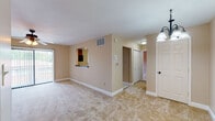 Located at 8 Hollandale Ln in Clifton Park, NY, this single-floor residence offers a well-organized and functional layout throughout. The living area is generously sized, featuring soft wall-to-wall carpeting in warm neutral tones, clean white baseboards, and an elegant chandelier that adds a refined touch to the space. A pass-through window connects the living area to the kitchen, enhancing the open feel between rooms. The kitchen is equipped with rich wood cabinetry, dark countertops, a tile backsplash, a coil-burner range with overhead microwave, and a ceiling fan, providing a practical and efficient cooking space. The bedrooms are carpeted and finished with the same warm neutral palette, each featuring ceiling fans with light fixtures and windows that invite natural light. Closet space is well provided throughout. A dedicated in-unit laundry closet houses a stacked washer and dryer, offering added convenience. The bathroom includes a full tub-shower combination with tile surround accents. Throughout the residence, consistent warm beige tones, clean white trim, and tasteful lighting create a comfortable and cohesive ambiance.