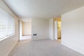 Located at 11412 NE 49th St in Vancouver, WA, this three-bedroom, two-bathroom residence offers a practical and well-organized layout across its single level of living space. The kitchen is a functional highlight, featuring rich dark-wood cabinetry, light-toned countertops, stainless steel appliances including a refrigerator, range, and dishwasher, and easy-care wood-look flooring that lends a clean, modern aesthetic. Adjacent to the kitchen, the living area offers plush carpeting and a wall-mounted heating unit, creating a comfortable, cohesive space for everyday living. The bedrooms are carpeted and finished with neutral tones, textured ceilings, and white trim, with the primary bedroom offering a modest yet functional footprint. Both bathrooms are neatly appointed with dark-framed vanity mirrors, white quartz-style countertops, dark wood cabinetry beneath the sinks, and a full tub-shower combination in the full bath. A carpeted staircase with a clean white railing connects levels within the home. Throughout the residence, the consistent use of neutral colors and practical finishes creates a cohesive, understated atmosphere suited to comfortable daily living.